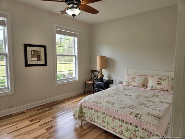 bedroom featuring multiple windows, ceiling fan, and light wood-type flooring