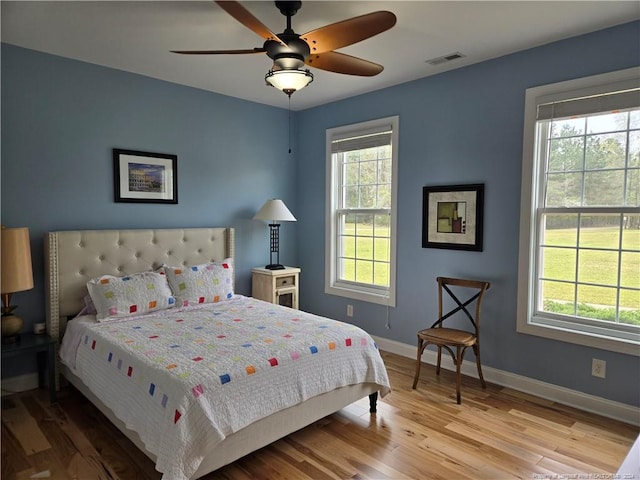 bedroom with multiple windows, ceiling fan, and light hardwood / wood-style flooring