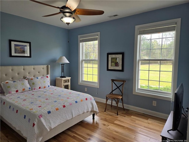 bedroom with multiple windows, ceiling fan, and light hardwood / wood-style flooring