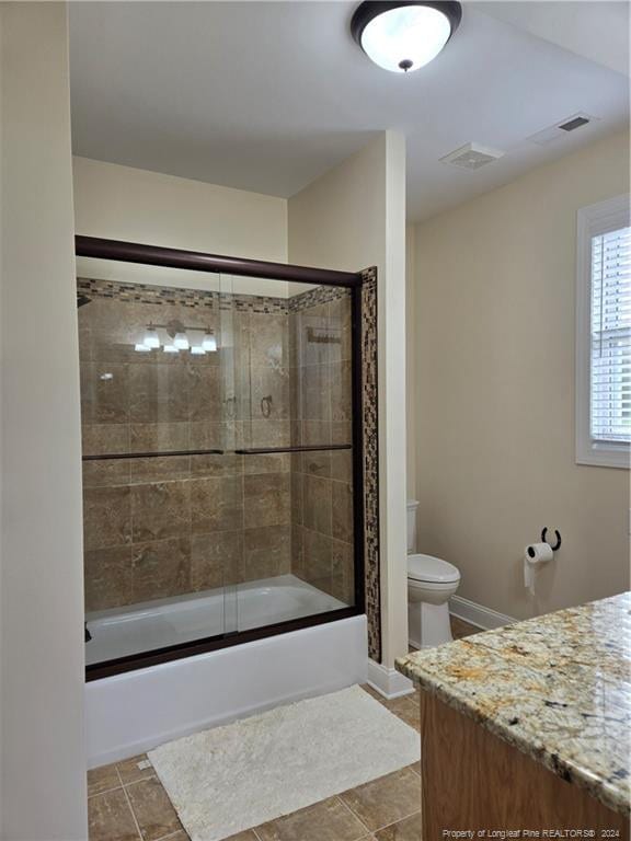 full bathroom with vanity, shower / bath combination with glass door, tile floors, and toilet