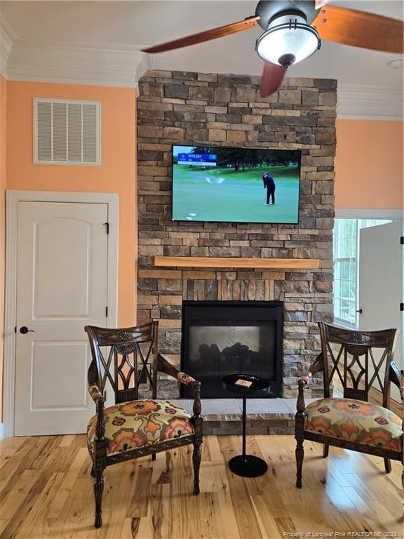 sitting room featuring ornamental molding, ceiling fan, light wood-type flooring, and a fireplace