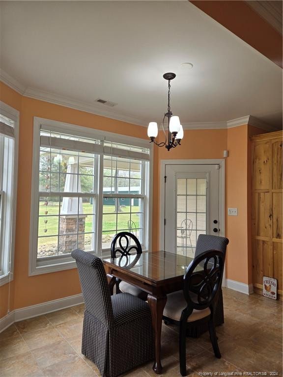 dining room featuring light tile flooring, ornamental molding, a notable chandelier, and a wealth of natural light