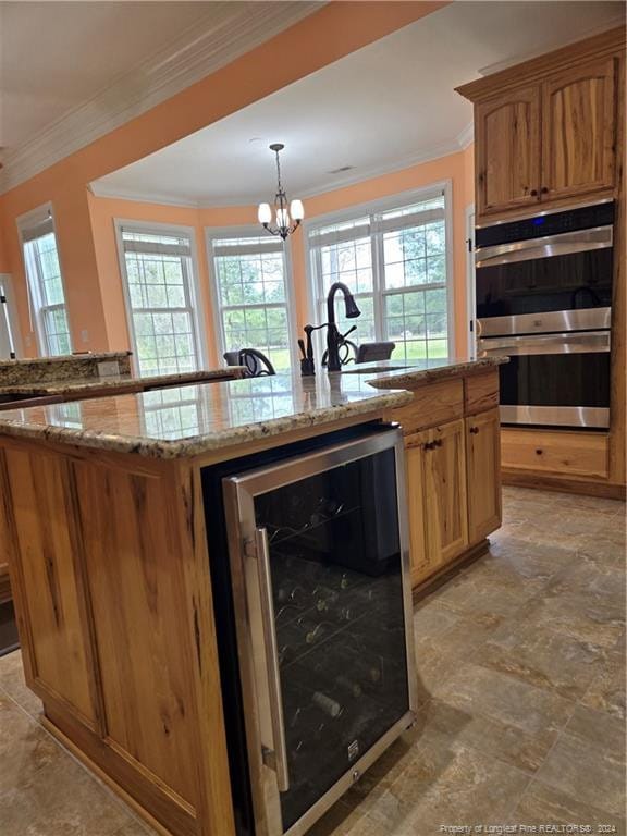 kitchen featuring pendant lighting, stainless steel double oven, a center island with sink, beverage cooler, and a notable chandelier