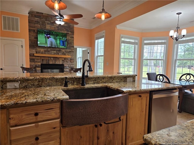 kitchen with pendant lighting, a stone fireplace, light stone counters, and ceiling fan with notable chandelier