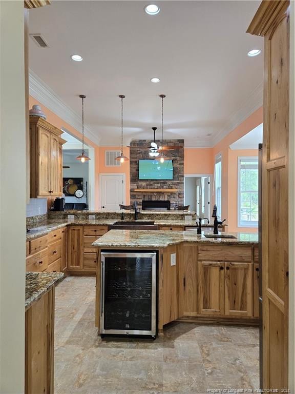 kitchen with hanging light fixtures, sink, a fireplace, and wine cooler