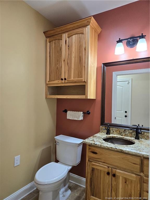 bathroom featuring tile flooring, toilet, and vanity