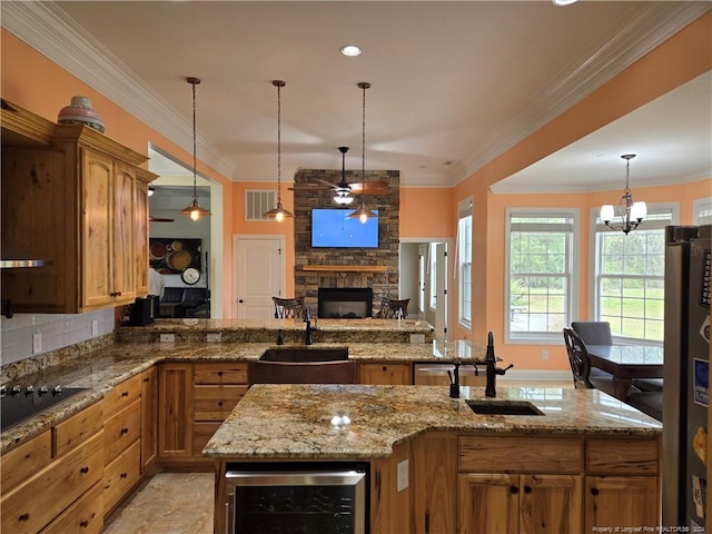 kitchen with sink, ornamental molding, black electric cooktop, wine cooler, and a stone fireplace