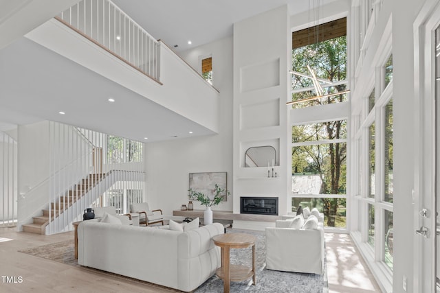 1435 Duplin Rd, Raleigh, NC 27607 - living room featuring a towering ceiling, a glass covered fireplace, wood finished floors, stairway, and recessed lighting