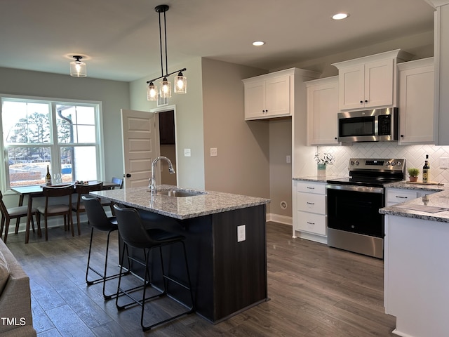 kitchen featuring white cabinets, appliances with stainless steel finishes, a center island with sink, and sink