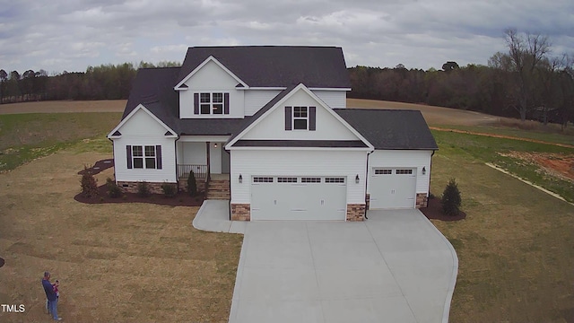 traditional home with driveway, a front yard, a garage, and a wooded view