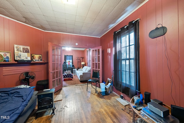 interior space with wooden walls, french doors, ornamental molding, and hardwood / wood-style floors