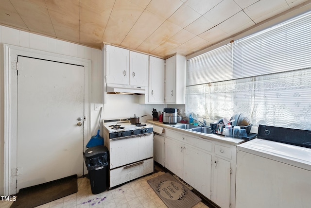 kitchen with light tile floors, white cabinets, sink, washer / dryer, and white range with gas cooktop