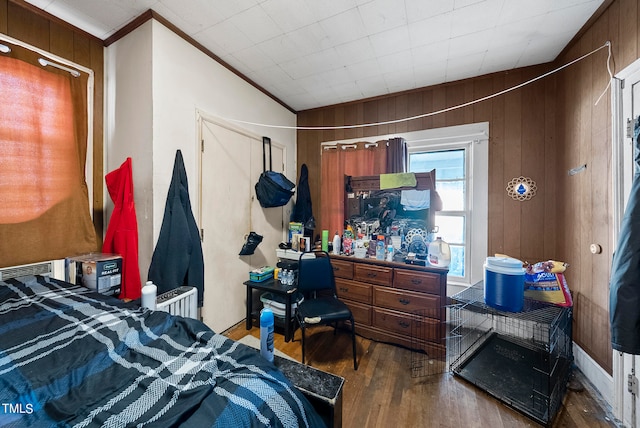 bedroom with ornamental molding, wood walls, and hardwood / wood-style floors