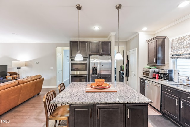 kitchen featuring a kitchen island, pendant lighting, stainless steel appliances, and light wood-type flooring