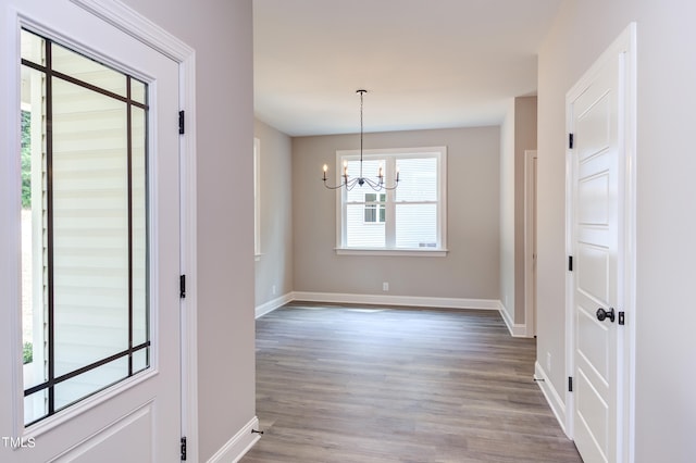 unfurnished dining area featuring a chandelier and wood-type flooring