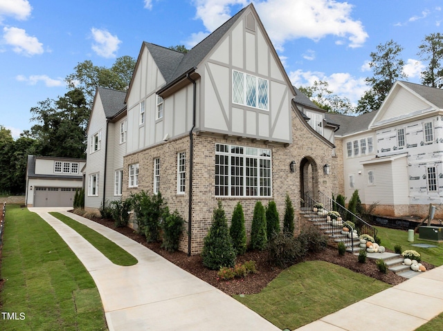 tudor home featuring a garage and a front lawn