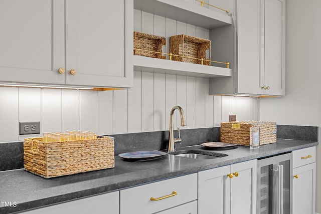 kitchen with white cabinets, beverage cooler, and sink