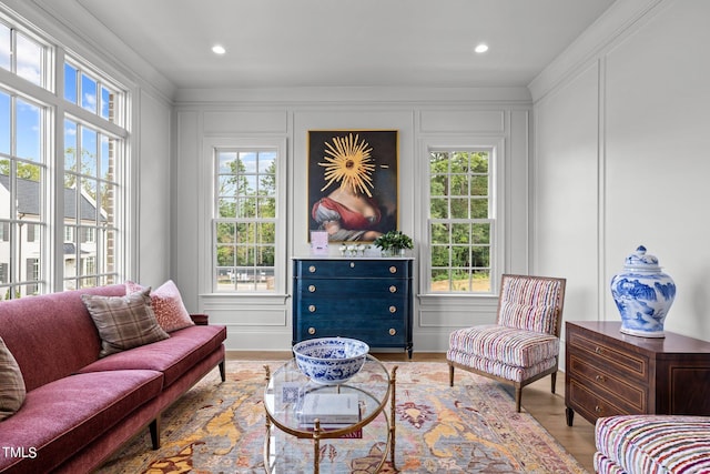 living area featuring light wood-type flooring, crown molding, and a healthy amount of sunlight