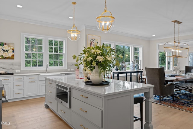 kitchen with decorative backsplash, light hardwood / wood-style floors, a center island, decorative light fixtures, and sink