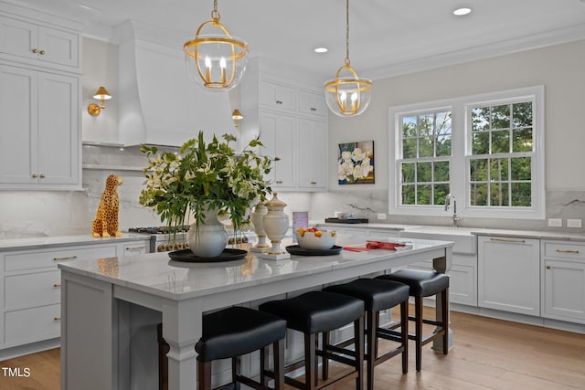 kitchen featuring light stone counters, a center island, tasteful backsplash, a breakfast bar area, and white cabinets