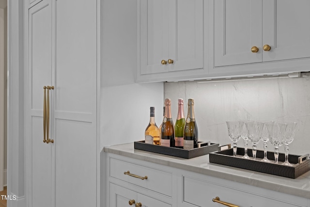 bar featuring backsplash and white cabinetry