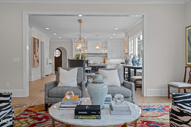 living room featuring ornamental molding, light hardwood / wood-style flooring, and a chandelier