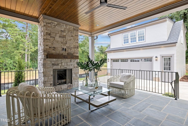 view of patio / terrace with a garage, ceiling fan, and an outdoor stone fireplace