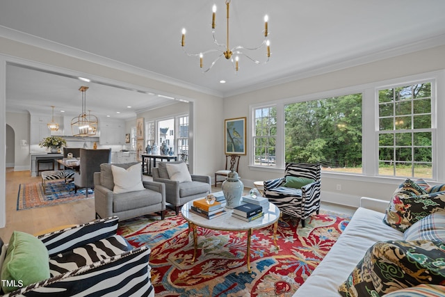 living room with ornamental molding, an inviting chandelier, and light hardwood / wood-style flooring