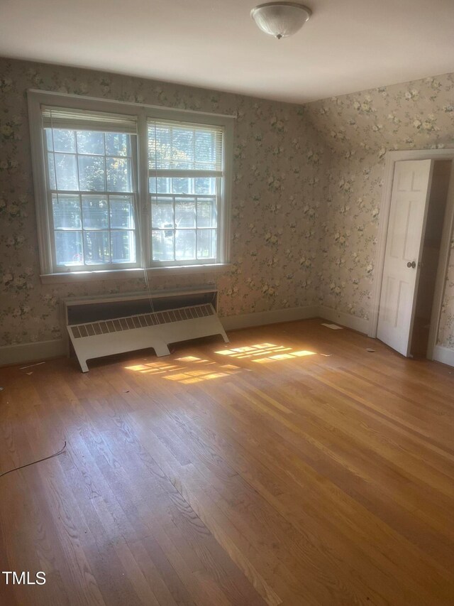 spare room featuring hardwood / wood-style floors and radiator