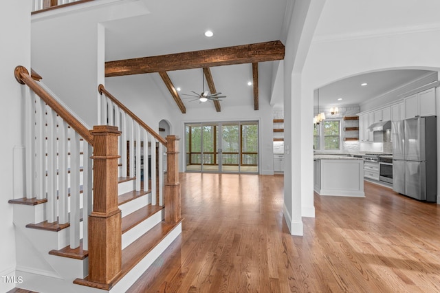 stairs with vaulted ceiling with beams, wood-type flooring, ornamental molding, and ceiling fan