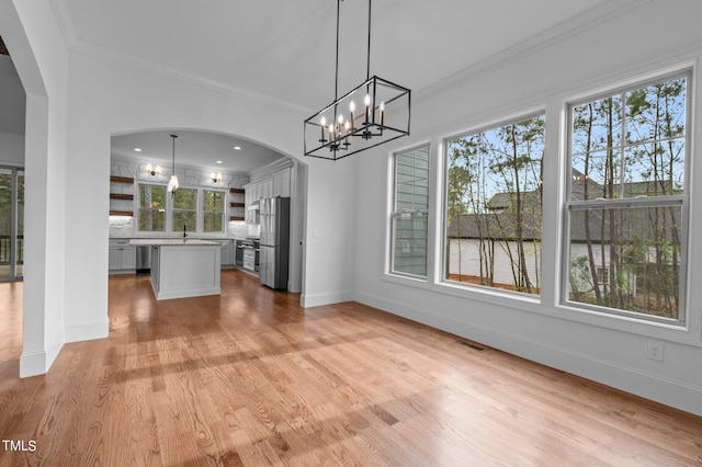 kitchen with a center island, hanging light fixtures, a healthy amount of sunlight, and stainless steel refrigerator