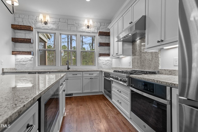 kitchen with white cabinets, crown molding, decorative backsplash, stainless steel appliances, and dark hardwood / wood-style flooring