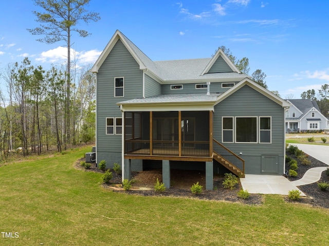 rear view of house featuring central AC unit, a sunroom, and a yard