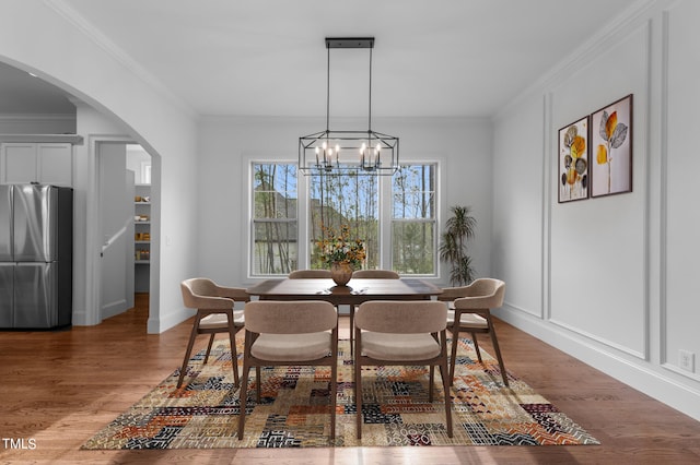 dining room featuring crown molding, an inviting chandelier, and hardwood / wood-style flooring