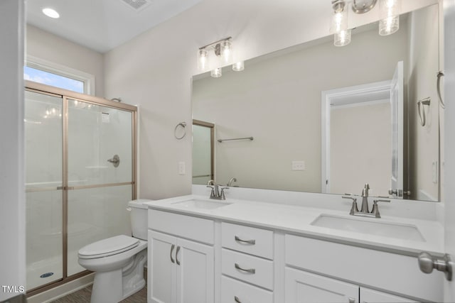 bathroom with a shower with door, toilet, oversized vanity, and dual sinks