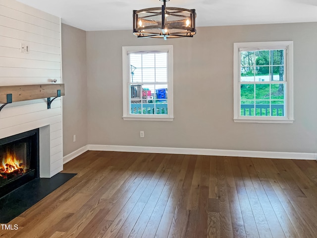 unfurnished living room with dark wood-type flooring and a chandelier