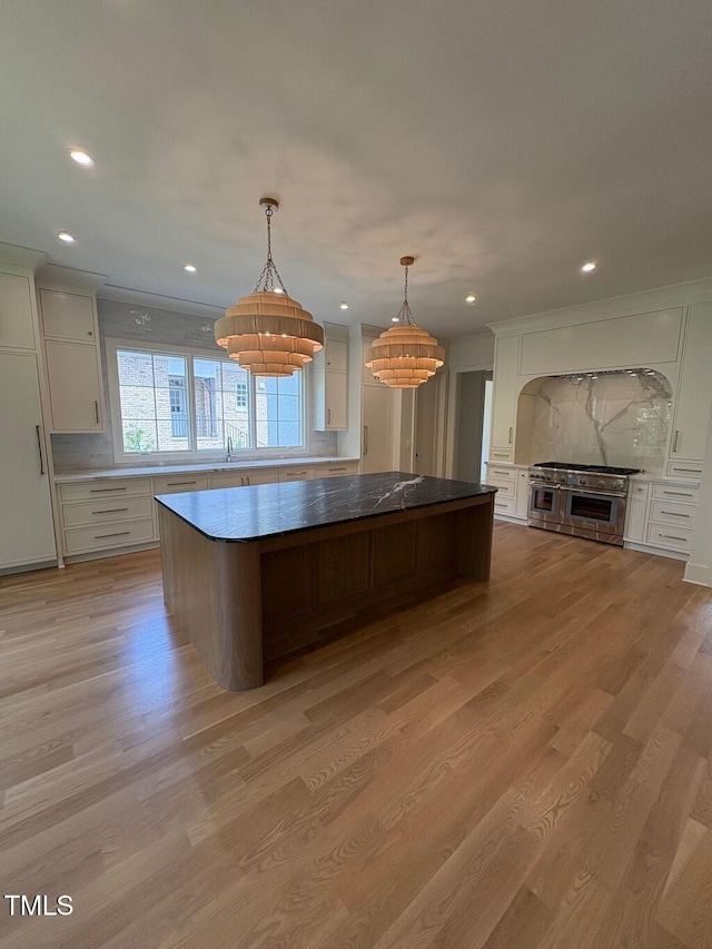 2227 Wheeler Rd, Raleigh, NC 27607 - kitchen featuring range with two ovens, a kitchen island, white cabinetry, tasteful backsplash, and light wood-type flooring