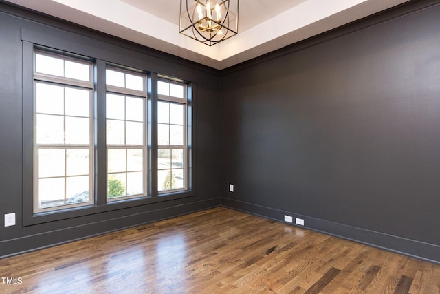 empty room with hardwood / wood-style floors and an inviting chandelier