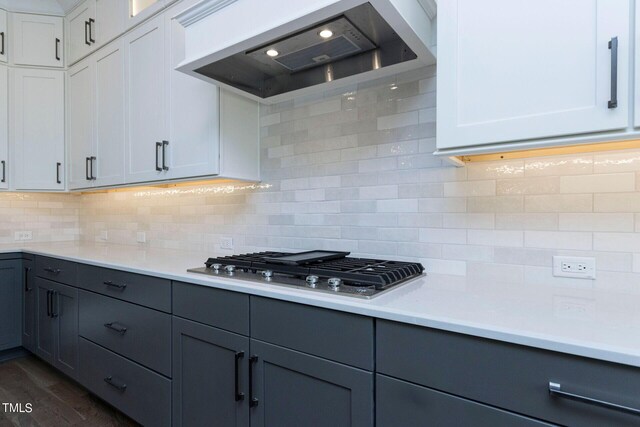 kitchen with wall chimney exhaust hood, stainless steel gas cooktop, white cabinetry, dark hardwood / wood-style flooring, and decorative backsplash