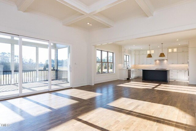 unfurnished living room featuring dark wood-type flooring, a water view, coffered ceiling, and beam ceiling