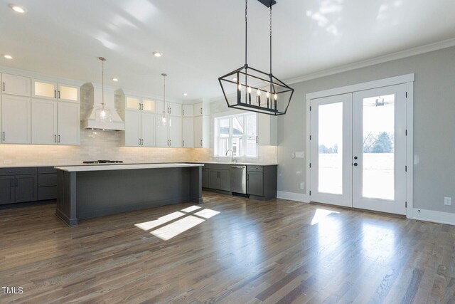 kitchen featuring premium range hood, white cabinetry, a center island, and stainless steel dishwasher