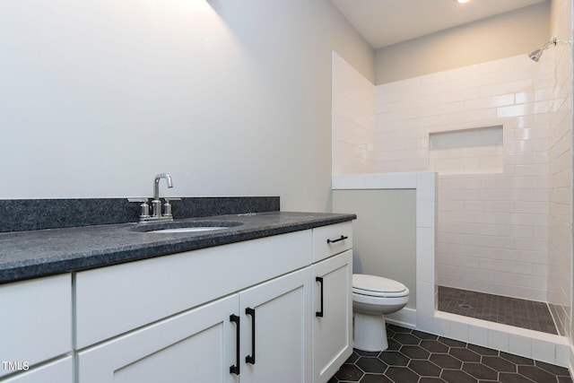 bathroom with vanity, toilet, tile patterned flooring, and a tile shower