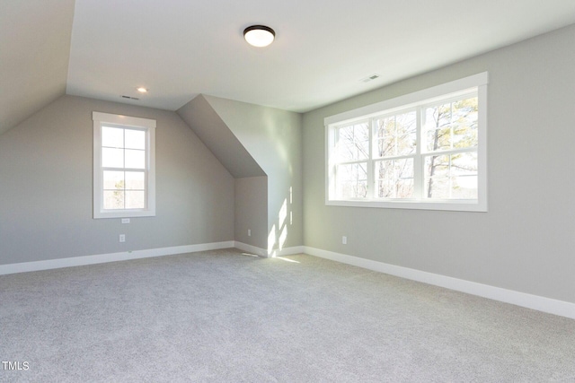 bonus room with light colored carpet and vaulted ceiling