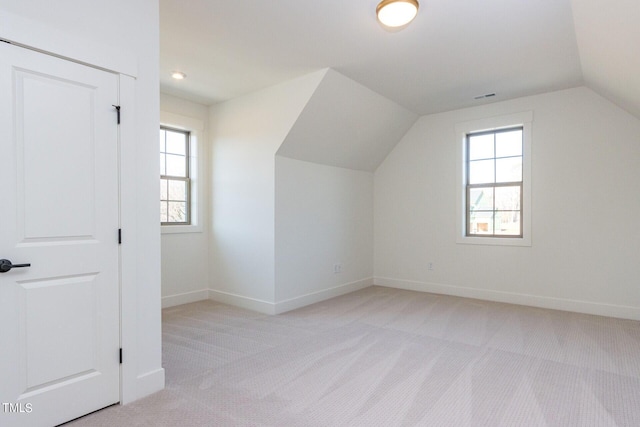 bonus room with lofted ceiling and light colored carpet