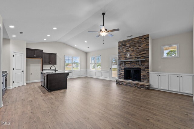 kitchen featuring a healthy amount of sunlight, a fireplace, wood-type flooring, and a kitchen island with sink