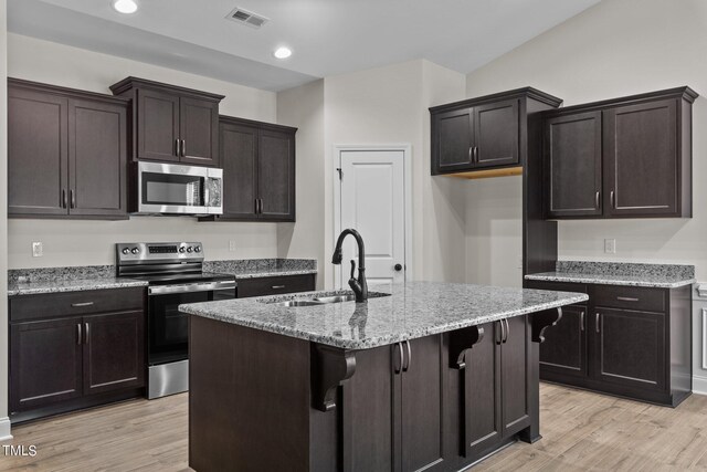 kitchen featuring light hardwood / wood-style floors, light stone countertops, appliances with stainless steel finishes, and sink