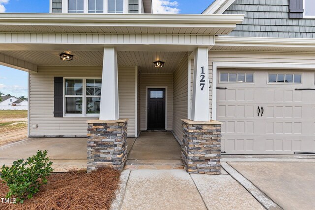 doorway to property featuring covered porch and a garage