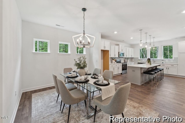 dining room with sink, dark wood-type flooring, and a chandelier