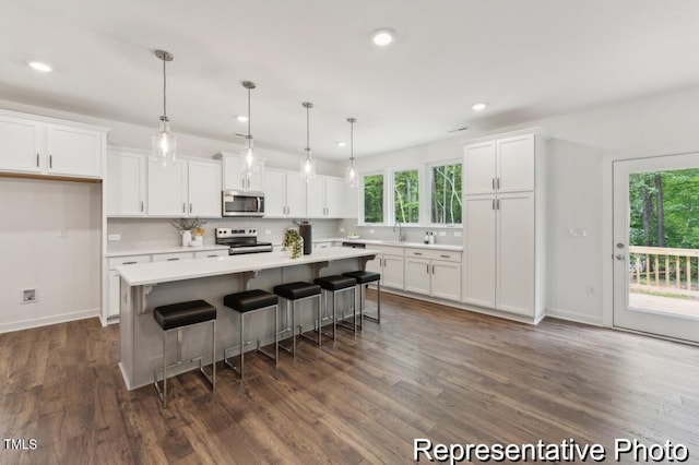 kitchen featuring white cabinets, a center island, appliances with stainless steel finishes, and dark hardwood / wood-style flooring