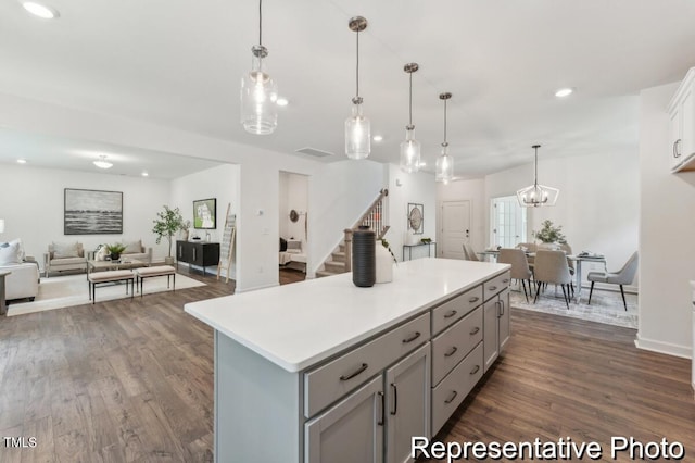 kitchen featuring pendant lighting, gray cabinets, a kitchen island, and dark hardwood / wood-style flooring